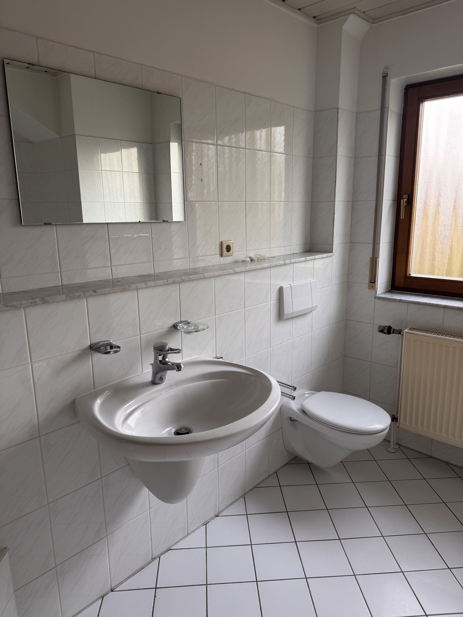 Praktisches Badezimmer mit Wandspiegel und zeitgemäßer Sanitärausstattung