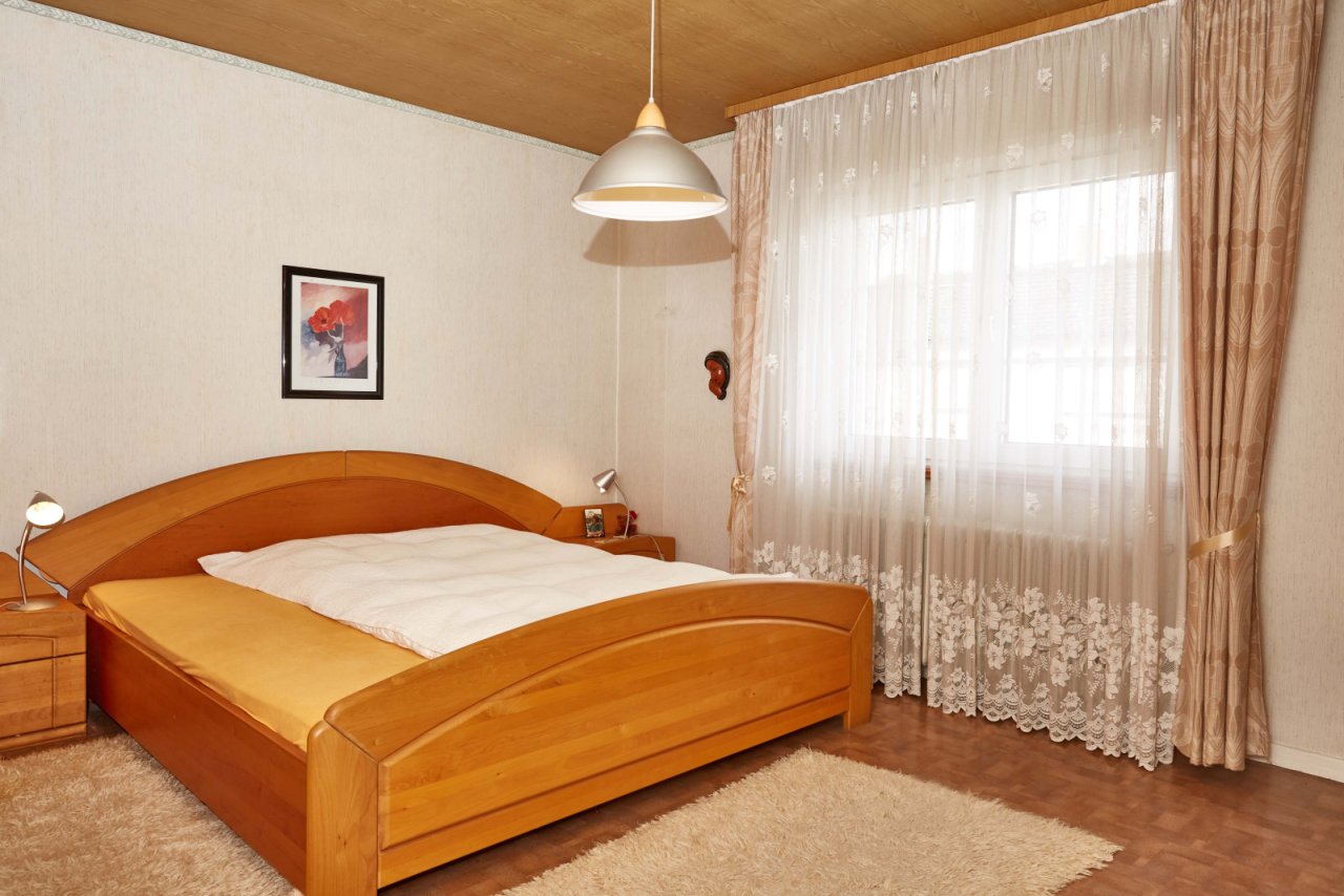 Helles Schlafzimmer mit großflächigen Fenstern und hochwertiger Ausstattung
