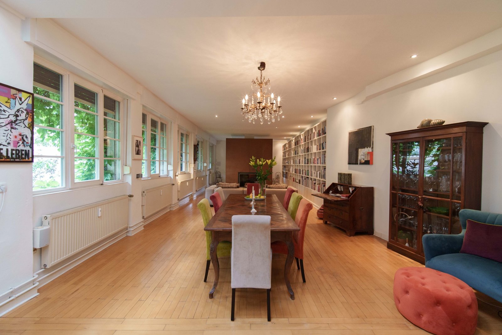 Bright living and dining area with an elegant bookshelf and a dreamy garden view Bright living and dining area with an elegant bookshelf and a dreamy garden view
