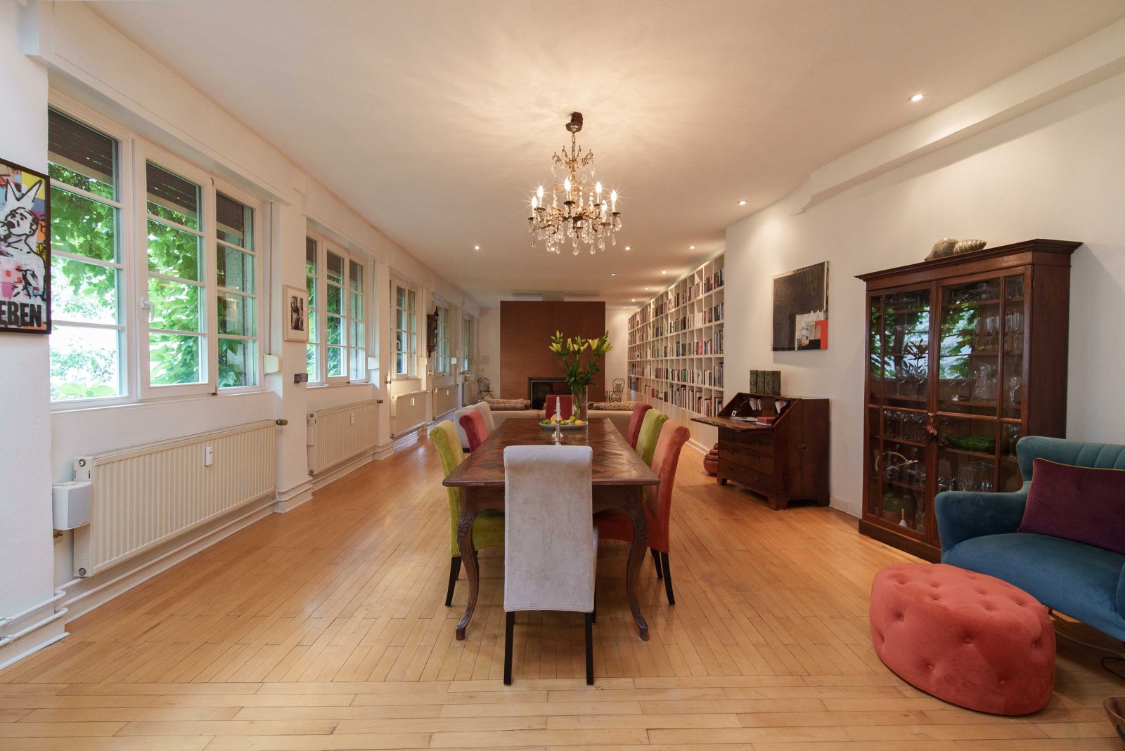 Bright living and dining area with an elegant library wall and a stunning garden view Bright living and dining area with an elegant library wall and a stunning garden view