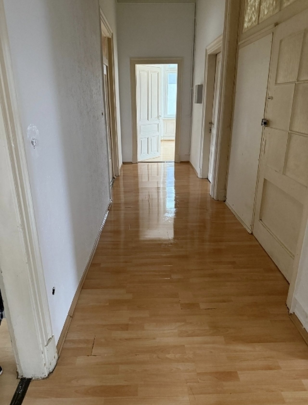 Brightly lit corridor with elegant parquet flooring - your entrance to comfort!
