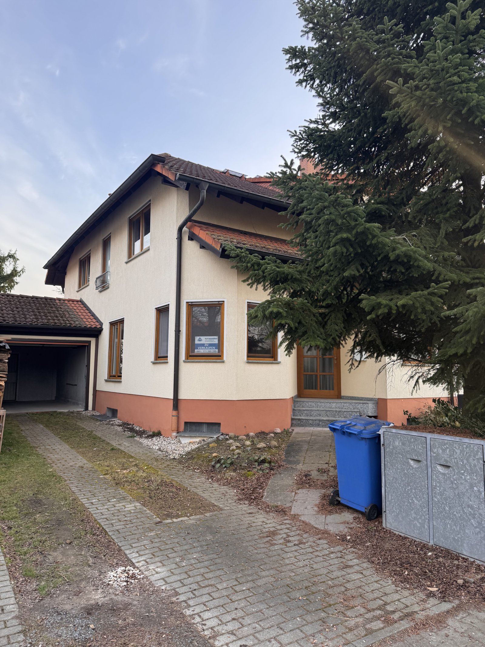 Well-maintained house entrance with paved access road and integrated garage