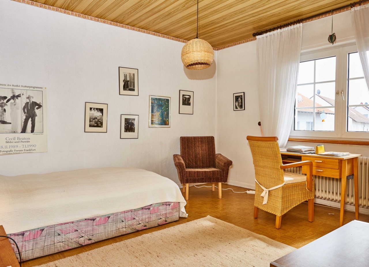 Bright bedroom with wooden ceiling and large windows across the entire wall.